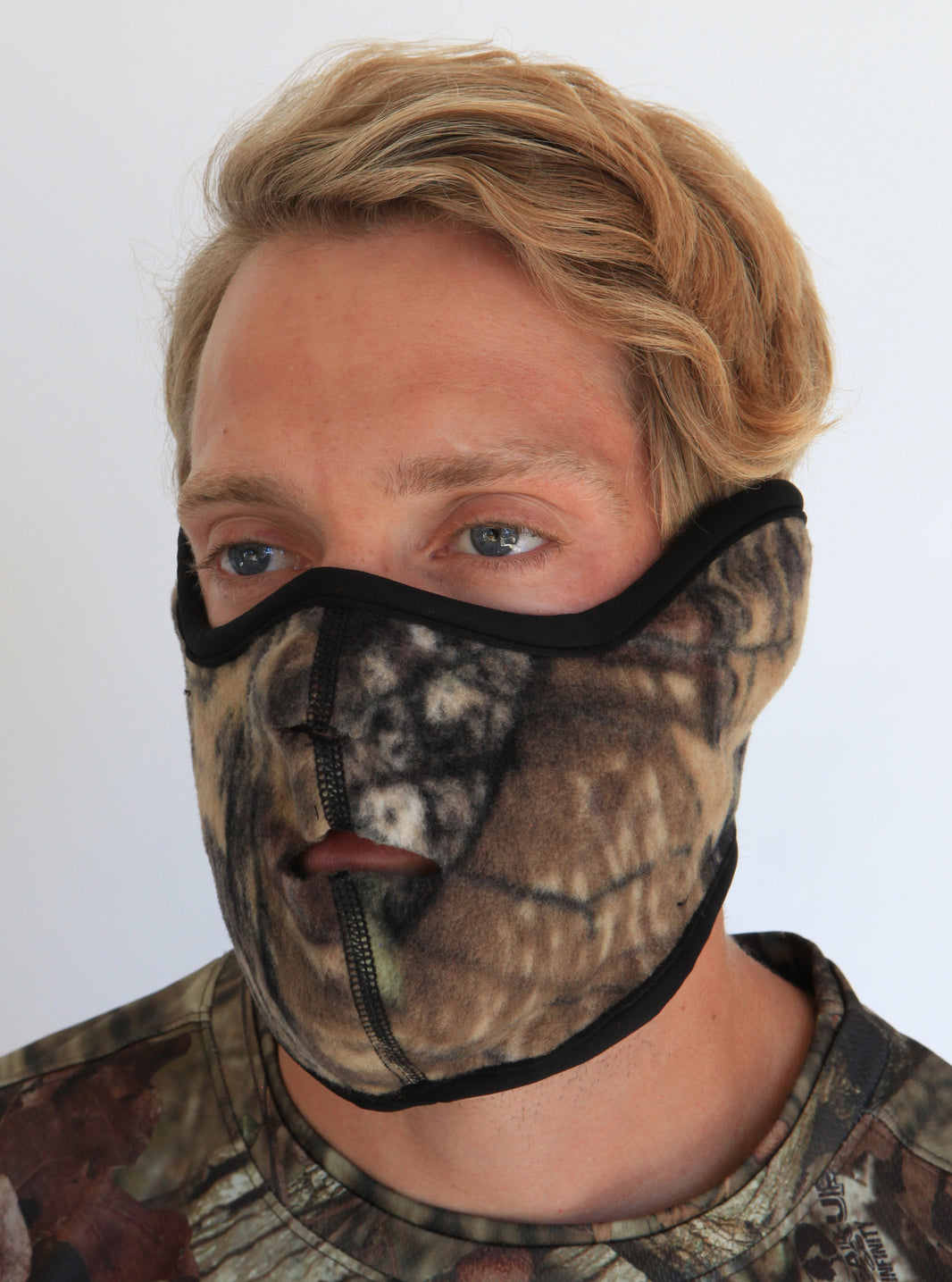 Person wearing a camouflage face mask against a white background