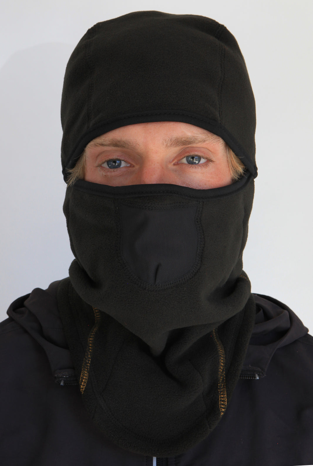 Person wearing a full-face black fleece balaclava with pockets for disposable air-activated warmers on a white background