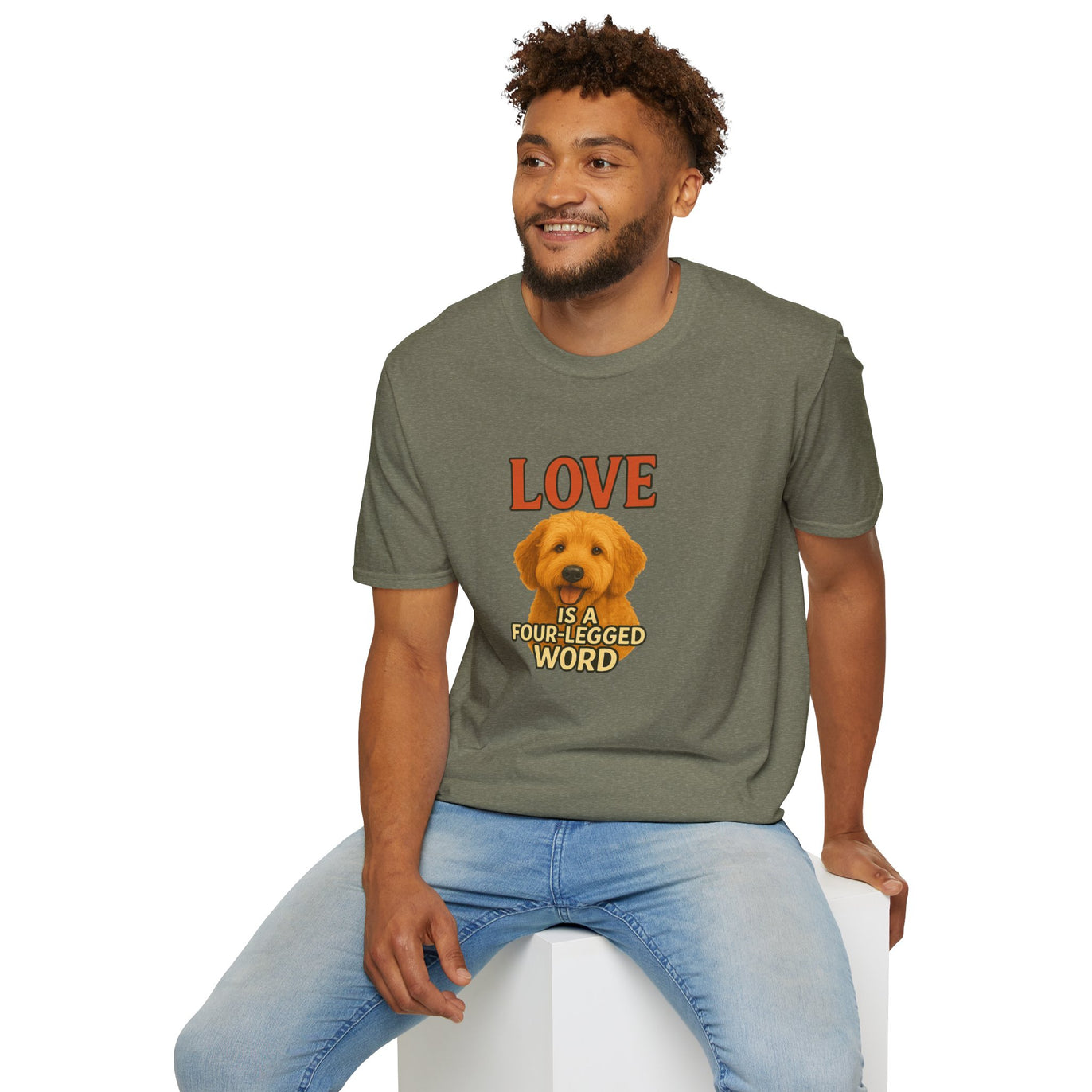 Man wearing a green t-shirt with a dog graphic and text, sitting on a white stool against a white background.