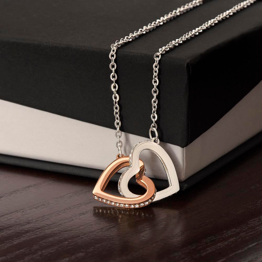 A silver necklace featuring two heart-shaped pendants with cubic zirconia crystals, displayed against a black background.