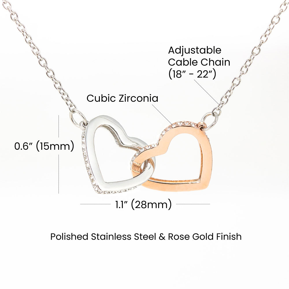A silver necklace featuring two heart-shaped pendants with cubic zirconia crystals, displayed against a black background.