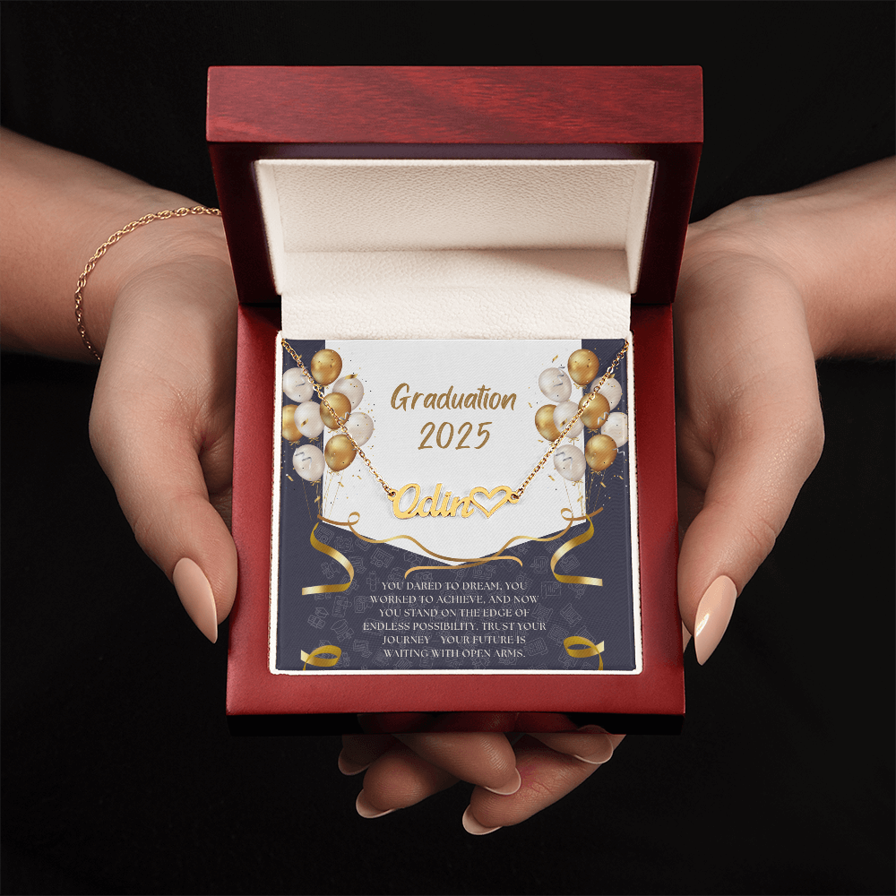 Close-up of hands holding an open red gift box featuring a personalized gold name necklace with heart, set against a message card that reads "Graduation 2025" and includes an inspiring graduation quote, with gold and white balloons in the background.
