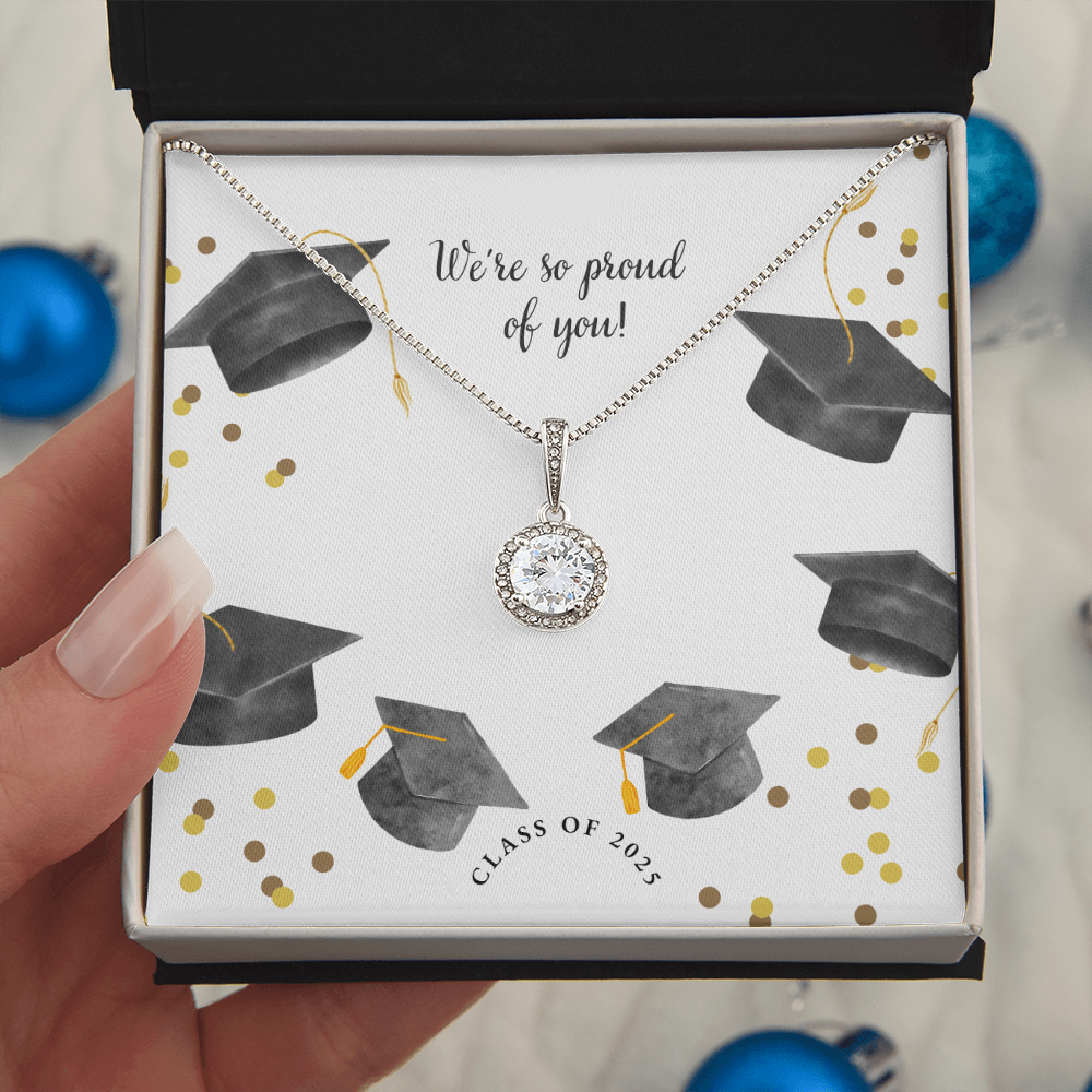 A hand holds an open gift box displaying a sparkling silver Eternal Hope necklace with a round pendant, set against a graduation-themed message card that reads "We're so proud of you!" with graduation caps, gold confetti, and "Class of 2025" text.