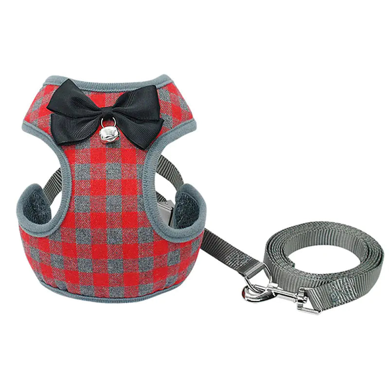 Red and gray checkered dog harness with a black bow and bell, accompanied by a matching leash on a white background.