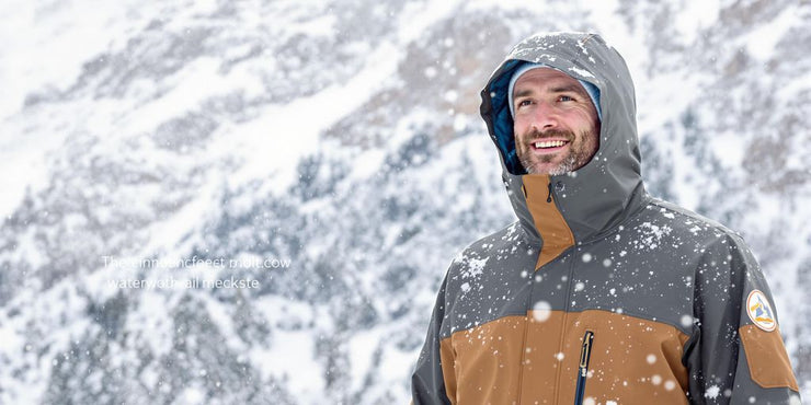 Man in cold weather rain jacket in snowy landscape.
