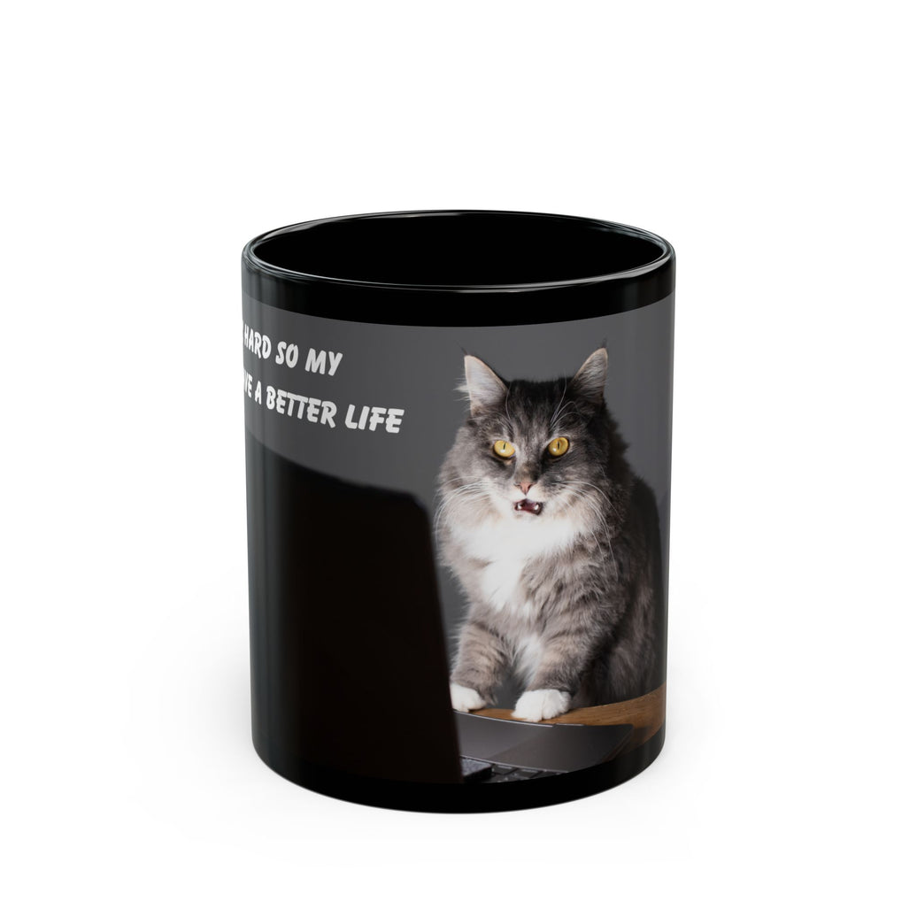 Black ceramic mug featuring a cartoon-style image of a cat sitting at a computer with the funny quote “I work hard so my cat can have a better life.”