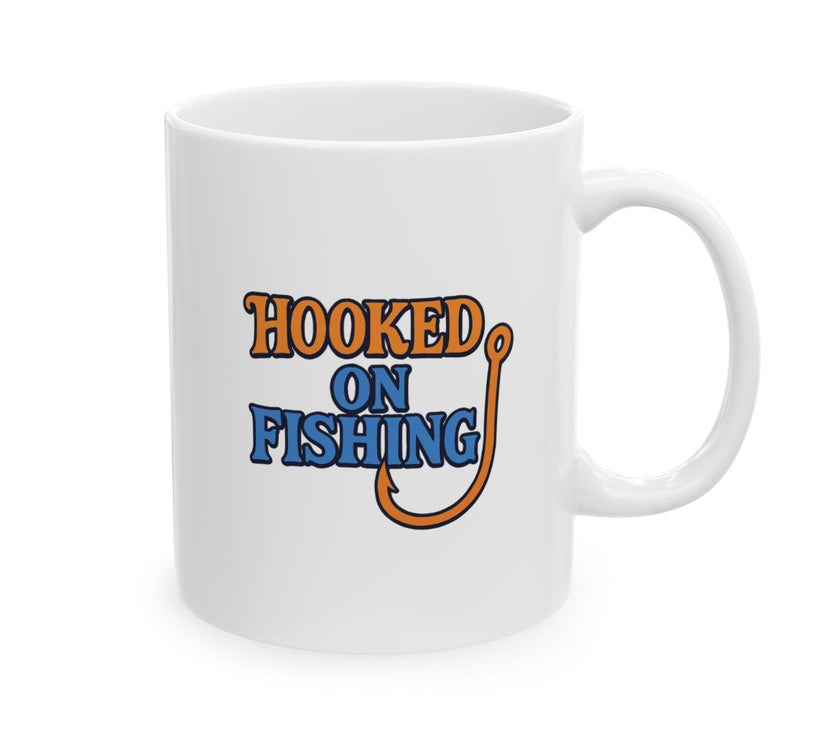 A white ceramic coffee mug displayed against a plain background, featuring the phrase "Hooked on Fishing" in bold orange and blue text with a graphic of a fishing hook integrated into the design.