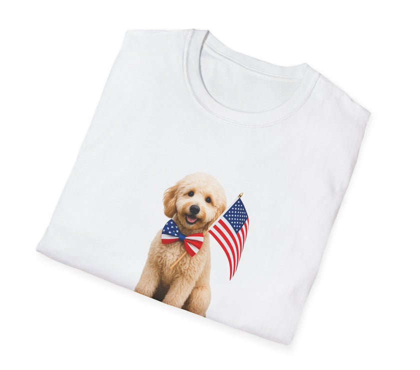 T-shirt featuring a cute golden doodle puppy wearing an American flag bow tie and holding a small U.S. flag, with the phrase 'Born to Be Free' printed below the image.  Folded T-shirt