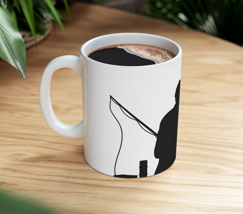 White ceramic mug featuring a silhouette of a child holding a fishing rod next to an adult figure, with the words "Happy Father's Day" in gold script above—an ideal gift for dads who love fishing and family time.