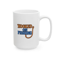 A white ceramic coffee mug displayed against a plain background, featuring the phrase "Hooked on Fishing" in bold orange and blue text with a graphic of a fishing hook integrated into the design.