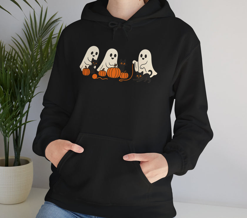 Person wearing a black hoodie with ghost and pumpkin design, standing indoors.