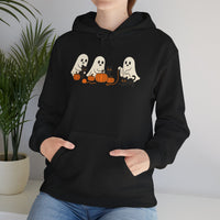 Person wearing a black hoodie with ghost and pumpkin design, standing indoors.