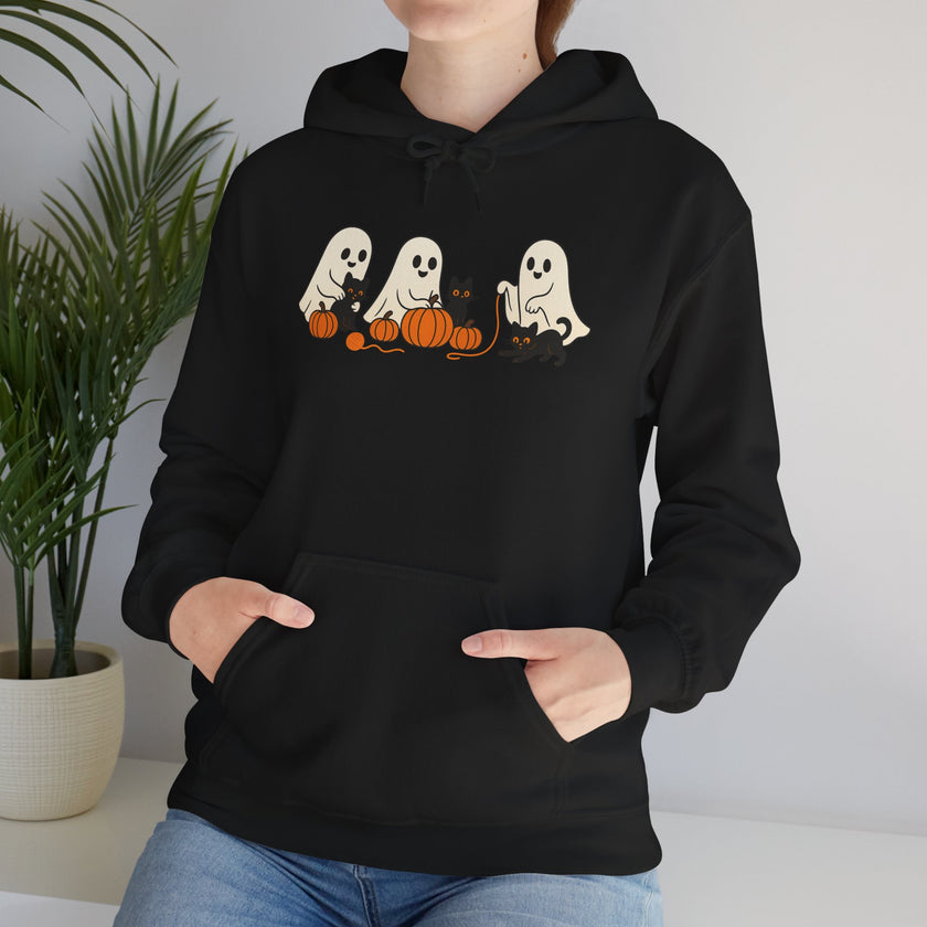 Person wearing a black hoodie with ghost and pumpkin design, standing indoors.