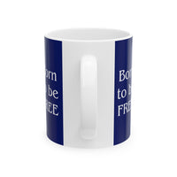 A ceramic mug featuring aGoldendoodle sitting on grass, wearing a red, white, and blue bow tie, and holding an American flag against a dark blue background. with the message "Born to be Free"