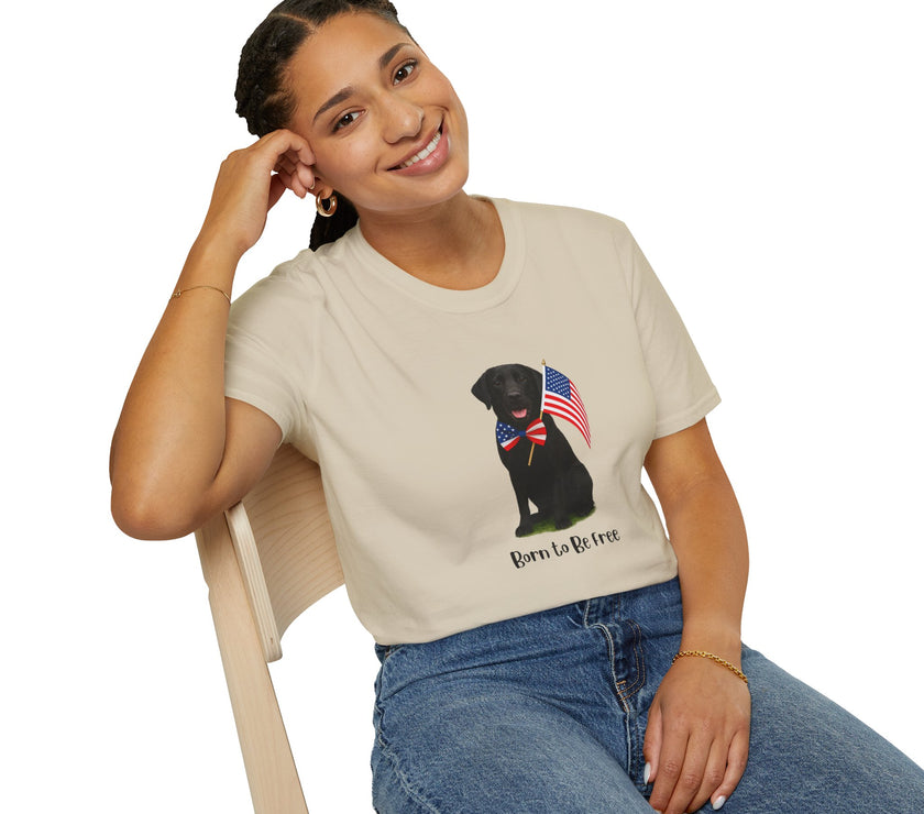 Sand t-shirt featuring a patriotic Black Lab wearing an American flag bowtie and holding U.S. flags, with the Black Labphrase "Born to Be Free" printed below — perfect for dog lovers and patriotic Americans.