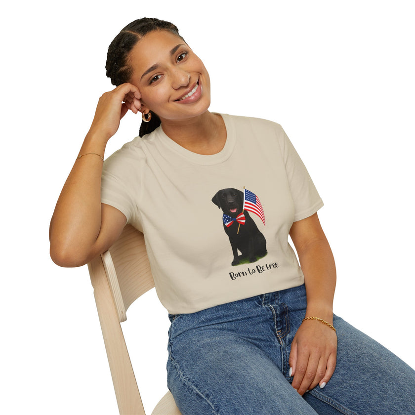 Sand t-shirt featuring a patriotic Black Lab wearing an American flag bowtie and holding U.S. flags, with the Black Labphrase "Born to Be Free" printed below — perfect for dog lovers and patriotic Americans.