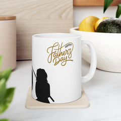 White ceramic mug featuring a silhouette of a child holding a fishing rod next to an adult figure, with the words "Happy Father's Day" in gold script above—an ideal gift for dads who love fishing and family time.