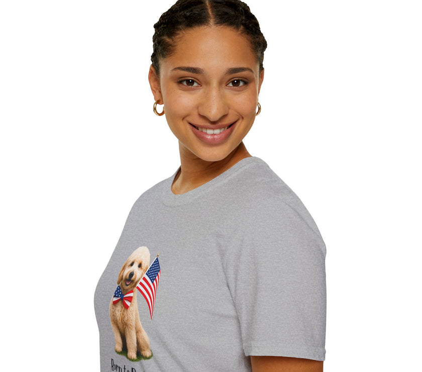 Female wearing T-shirt featuring a cute golden doodle puppy wearing an American flag bow tie and holding a small U.S. flag, with the phrase 'Born to Be Free' printed below the image.