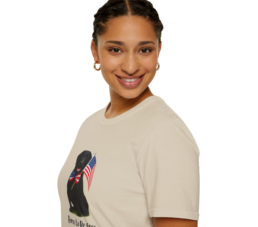 Sand t-shirt featuring a patriotic Black Lab wearing an American flag bowtie and holding U.S. flags, with the Black Labphrase "Born to Be Free" printed below — perfect for dog lovers and patriotic Americans.