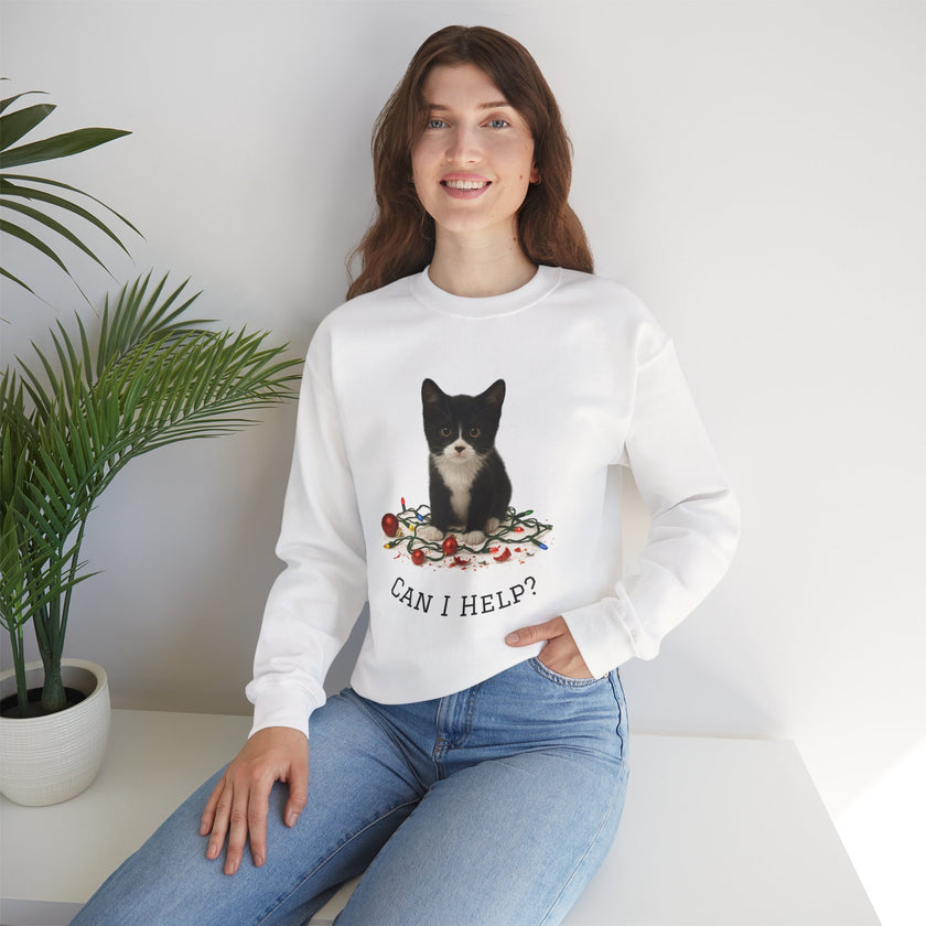 Woman wearing a white sweatshirt with a cat graphic and 'Can I Help?' text, sitting in a room with a plant.
