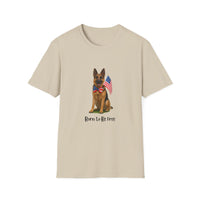 Beige t-shirt featuring a patriotic German Shepherd wearing an American flag bowtie and holding U.S. flags, with the phrase "Born to Be Free" printed below — perfect for dog lovers and patriotic Americans.