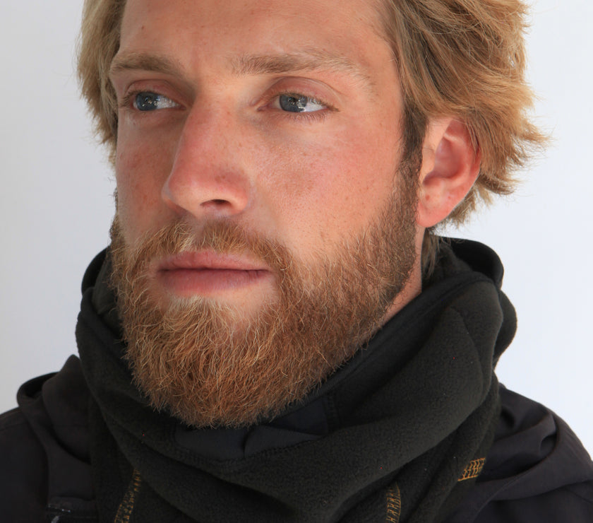 Person wearing a full-face black fleece balaclava with pockets for disposable air-activated warmers on a white background
