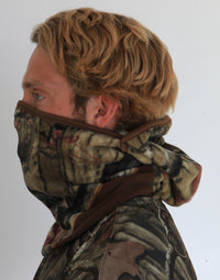 Person wearing a full-face camouflage fleece balaclava with pockets for disposable air-activated warmers on a white background