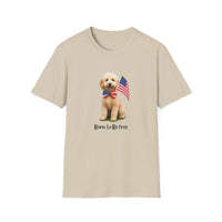 T-shirt featuring a cute golden doodle puppy wearing an American flag bow tie and holding a small U.S. flag, with the phrase 'Born to Be Free' printed below the image.