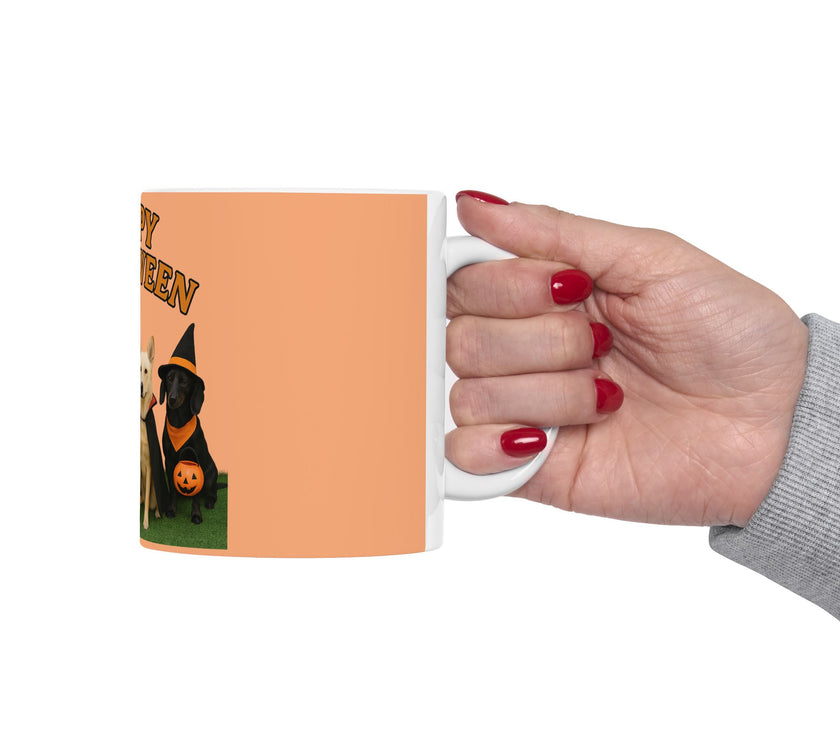 Hand holding a mug with a Halloween design of a black dog in a witch hat and pumpkin.