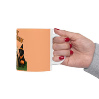 Hand holding a mug with a Halloween design of a black dog in a witch hat and pumpkin.