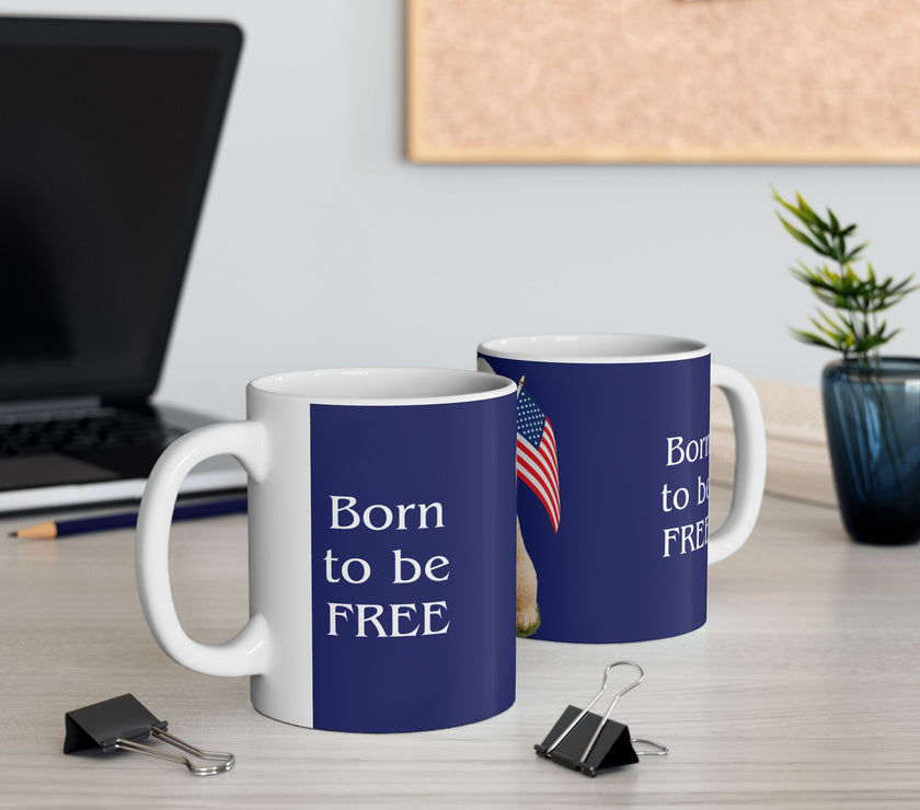 Two ceramic mugs featuring 
 a Goldendoodle sitting on grass, wearing a red, white, and blue bow tie, and holding an American flag against a dark blue background. with the message "Born to be Free"  side view
