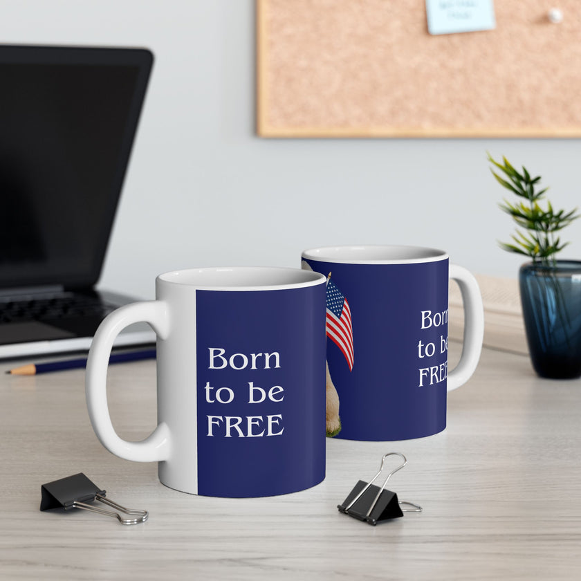 Two ceramic mugs featuring 
 a Goldendoodle sitting on grass, wearing a red, white, and blue bow tie, and holding an American flag against a dark blue background. with the message "Born to be Free"  side view
