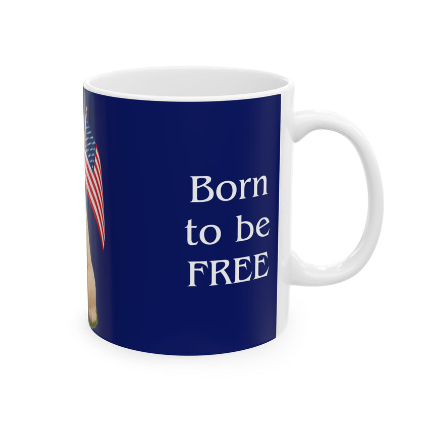 A ceramic mug featuring aGoldendoodle sitting on grass, wearing a red, white, and blue bow tie, and holding an American flag against a dark blue background. with the message "Born to be Free"  side view