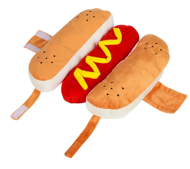 Plush toy shaped like a hot dog with bun, red body, and yellow mustard on a white background