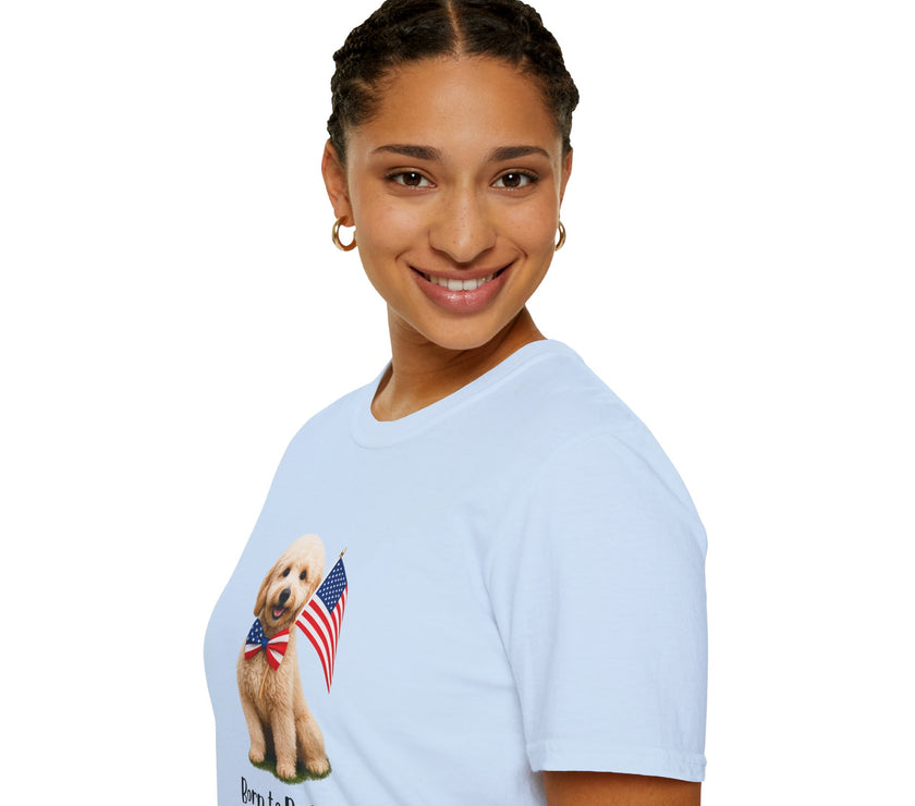 Female wearing T-shirt featuring a cute golden doodle puppy wearing an American flag bow tie and holding a small U.S. flag, with the phrase 'Born to Be Free' printed below the image.