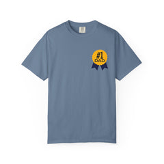 Jean color t-shirt featuring a yellow and navy blue award ribbon graphic on the chest with the text "#1 Dad," designed as a fun and heartfelt Father's Day gift.