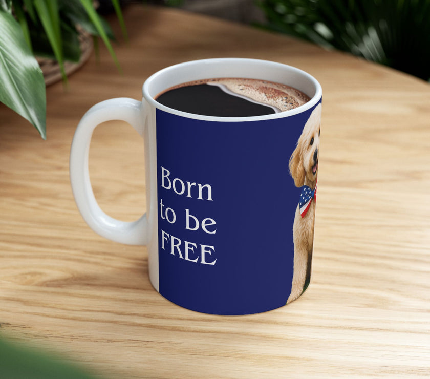 A ceramic mug featuring aGoldendoodle sitting on grass, wearing a red, white, and blue bow tie, and holding an American flag against a dark blue background. with the message "Born to be Free"  side view