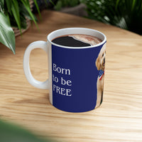 A ceramic mug featuring aGoldendoodle sitting on grass, wearing a red, white, and blue bow tie, and holding an American flag against a dark blue background. with the message "Born to be Free"  side view