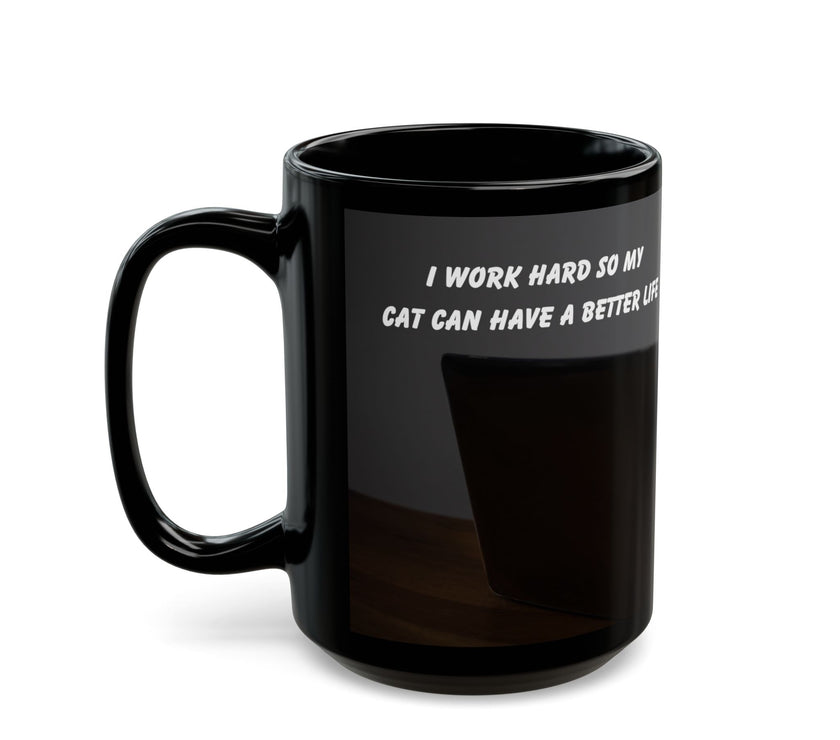Black ceramic mug featuring a cartoon-style image of a cat sitting at a computer with the funny quote “I work hard so my cat can have a better life.”