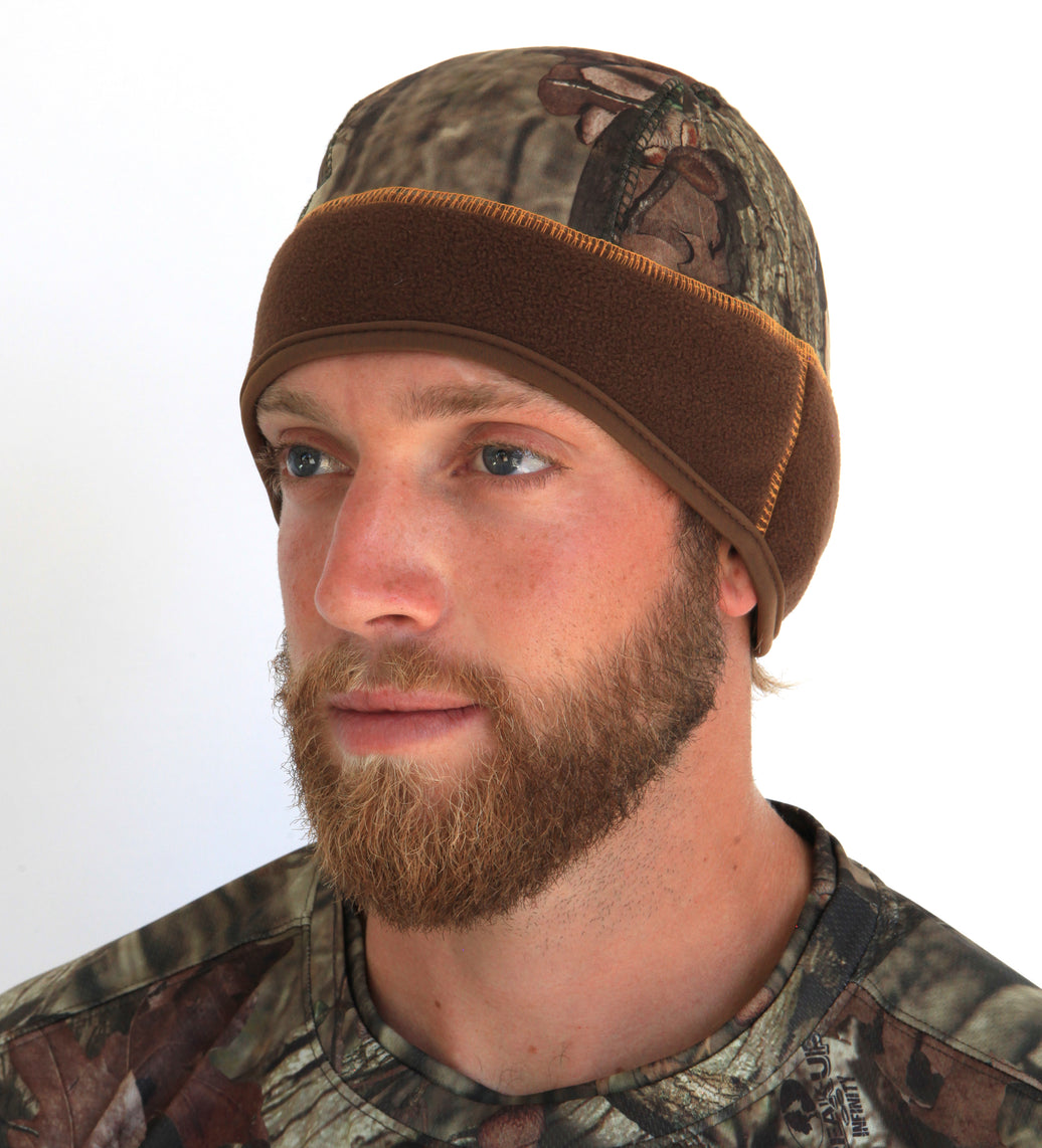 A man wearing a brown camouflage beanie with insulated pockets on the ears.