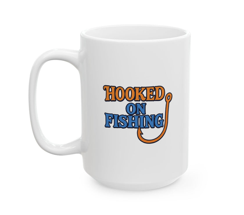 A white ceramic coffee mug displayed against a plain background, featuring the phrase "Hooked on Fishing" in bold orange and blue text with a graphic of a fishing hook integrated into the design.