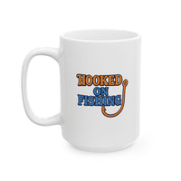 A white ceramic coffee mug displayed against a plain background, featuring the phrase "Hooked on Fishing" in bold orange and blue text with a graphic of a fishing hook integrated into the design.
