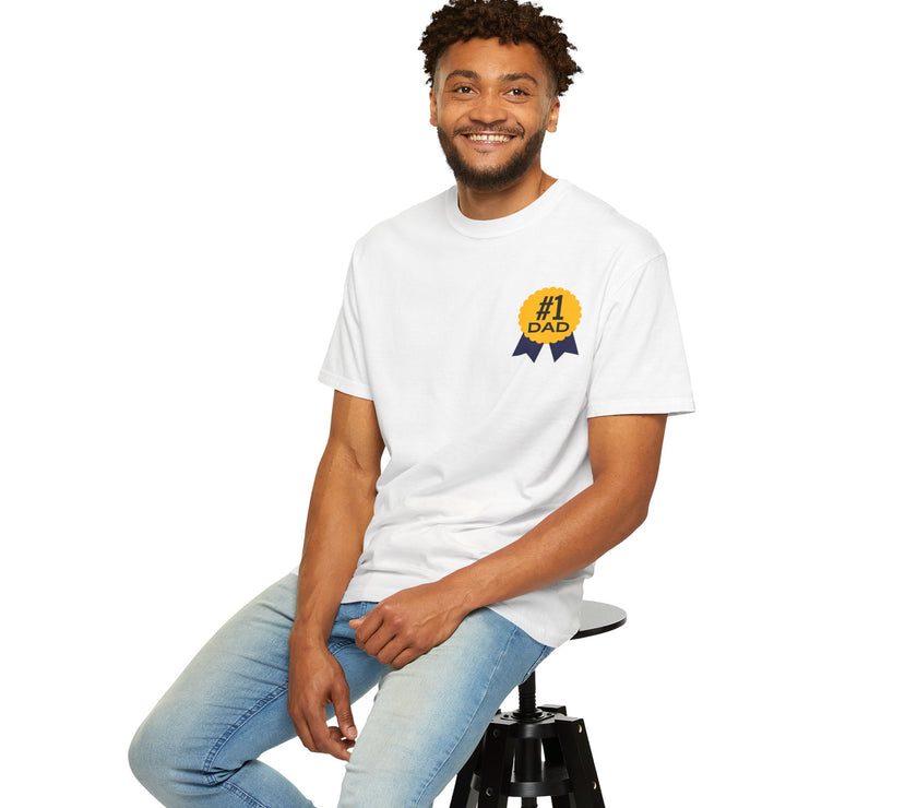 White t-shirt featuring a yellow and navy blue award ribbon graphic on the chest with the text "#1 Dad," designed as a fun and heartfelt Father's Day gift.