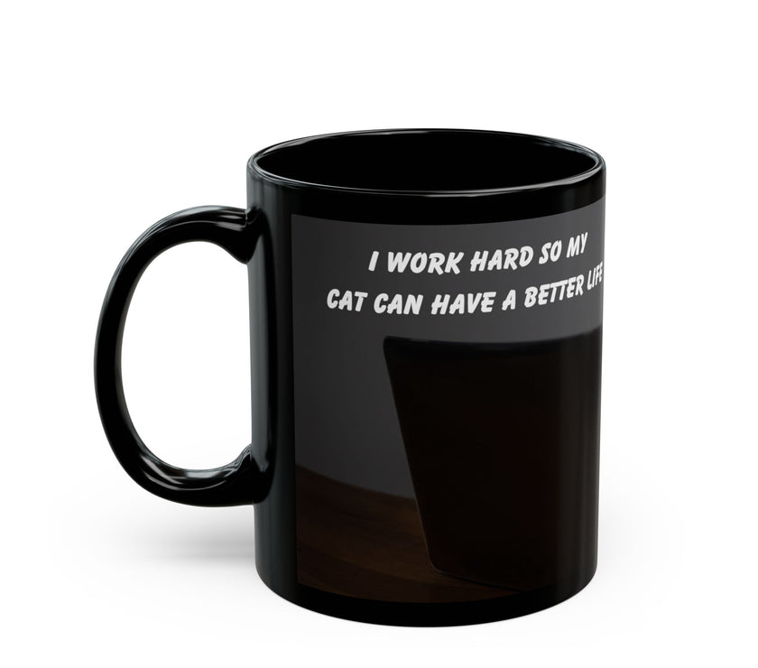 Black ceramic mug featuring a cartoon-style image of a cat sitting at a computer with the funny quote “I work hard so my cat can have a better life.”