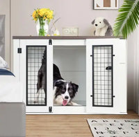 White pet crate with black grid doors in a room with a dog inside, a plant, and decorative items.