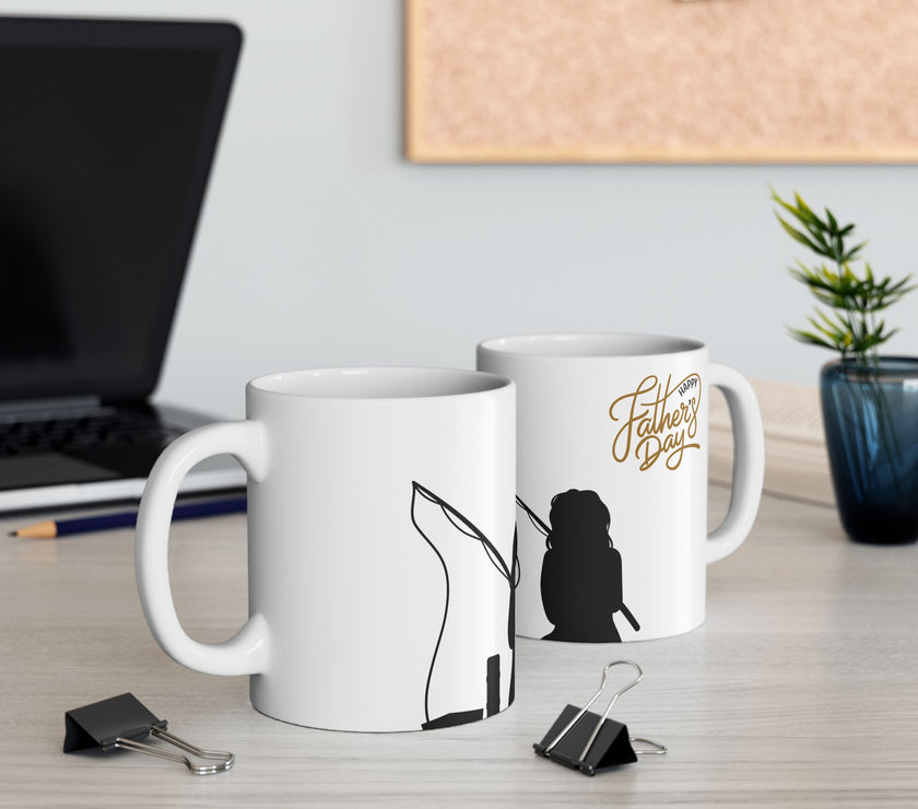 White ceramic mug featuring a silhouette of a child holding a fishing rod next to an adult figure, with the words "Happy Father's Day" in gold script above—an ideal gift for dads who love fishing and family time.
