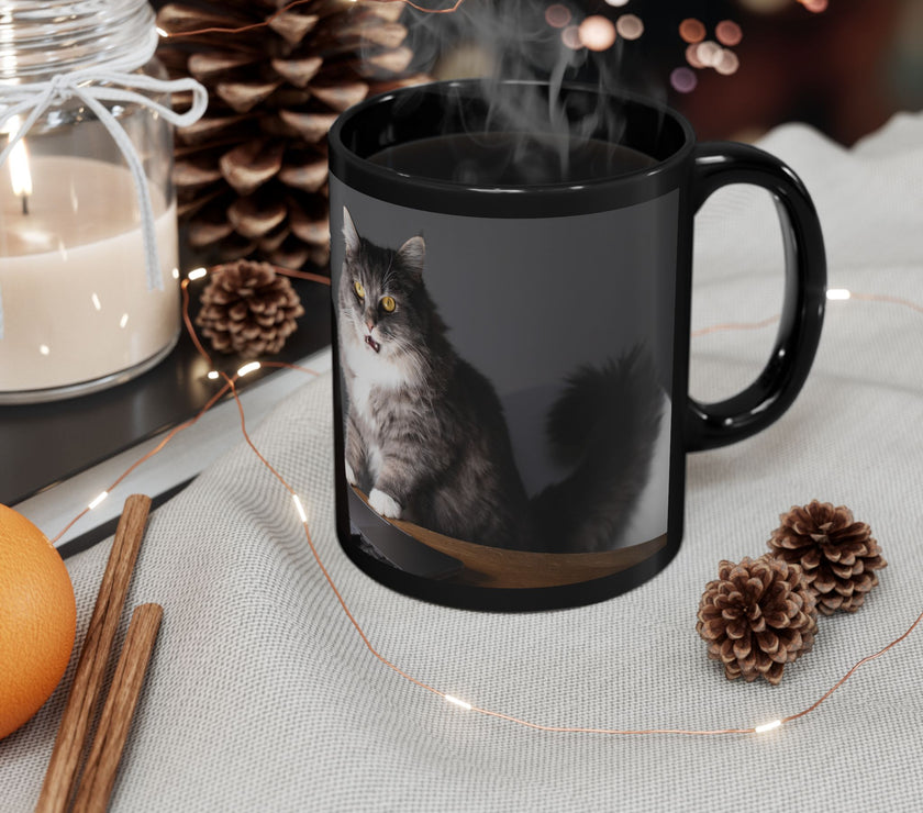 Black ceramic mug featuring a cartoon-style image of a cat sitting at a computer with the funny quote “I work hard so my cat can have a better life.”