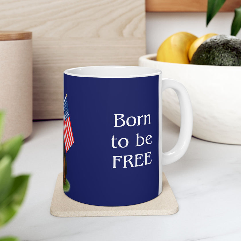 A ceramic mug featuring a Rottweiler sitting on grass, wearing a red, white, and blue bow tie, and holding an American flag against a dark blue background. with the message "Born to be Free"