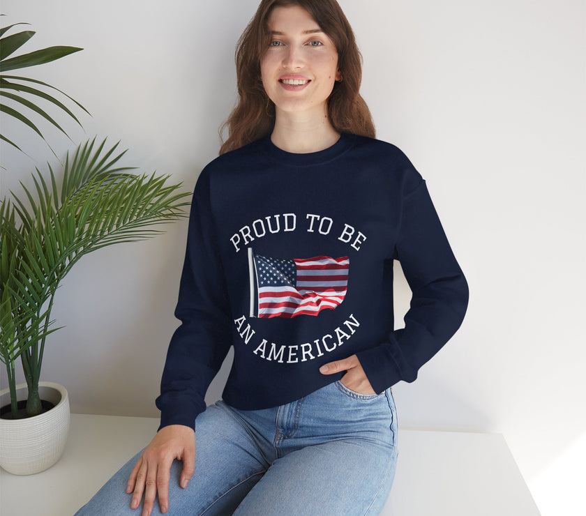 Person wearing a navy blue sweatshirt with 'Proud to be an American' text and flag design, sitting on a white surface with a plant in the background.