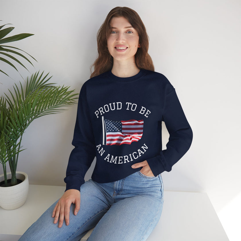 Person wearing a navy blue sweatshirt with 'Proud to be an American' text and flag design, sitting on a white surface with a plant in the background.